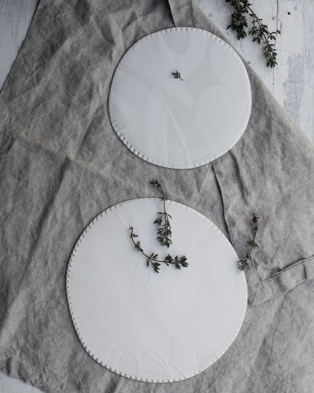 Flat ceramic plates with satin white glaze and textured rims