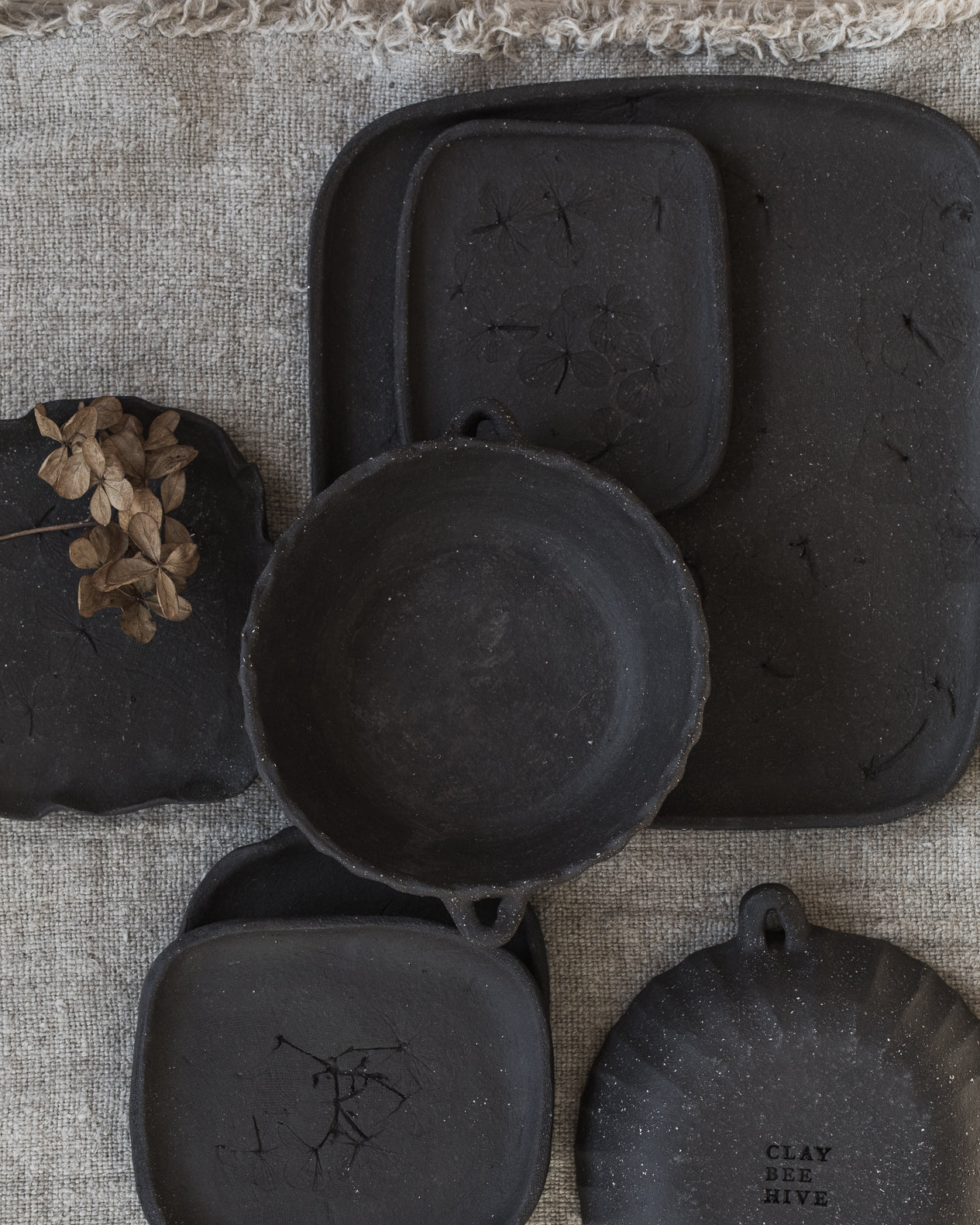 Handmade matte black small rectangular plates with hydrangea flower imprints, handmade by clay beehive ceramics.