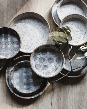 Mix of rustic high sided dinner plates and bowls in rustic glaze handmade by clay beehive ceramics
