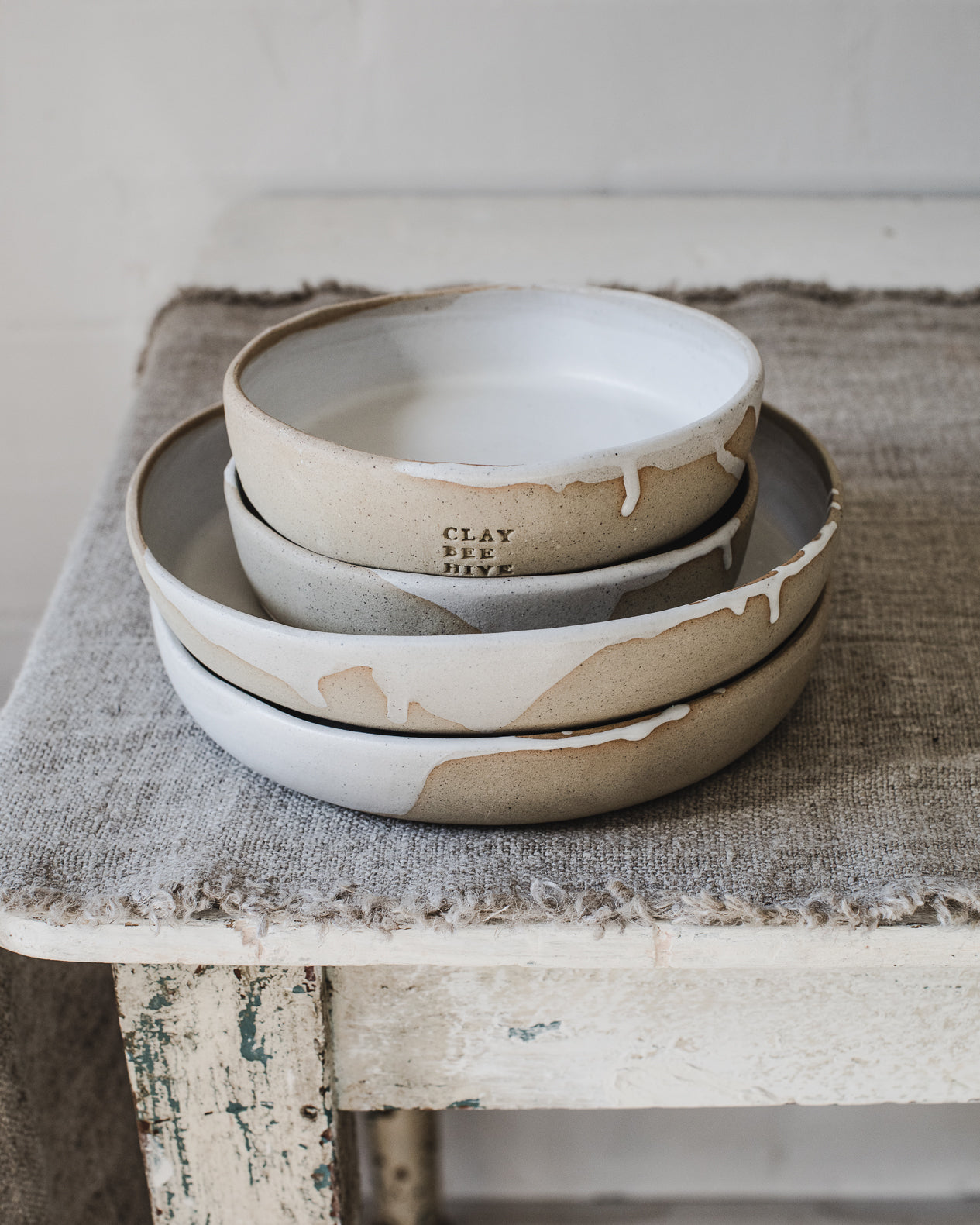 Deep dish plates handmade with a tan/speckled clay and glazed in a drippy satin white finish, created by clay beehive ceramics