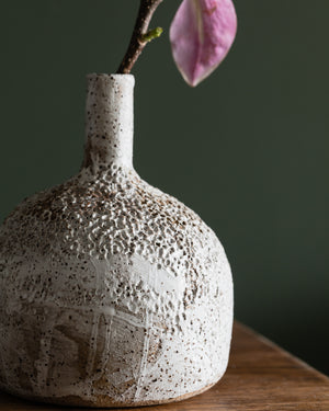 Large bottle shaped textured vase with long neck, glazed in a matte white finish, contrasting against the rustic speckled tan clay body, handmade by Clay Beehive ceramics. 