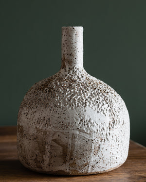 Large bottle shaped textured vase with long neck, glazed in a matte white finish, contrasting against the rustic speckled tan clay body, handmade by Clay Beehive ceramics. 