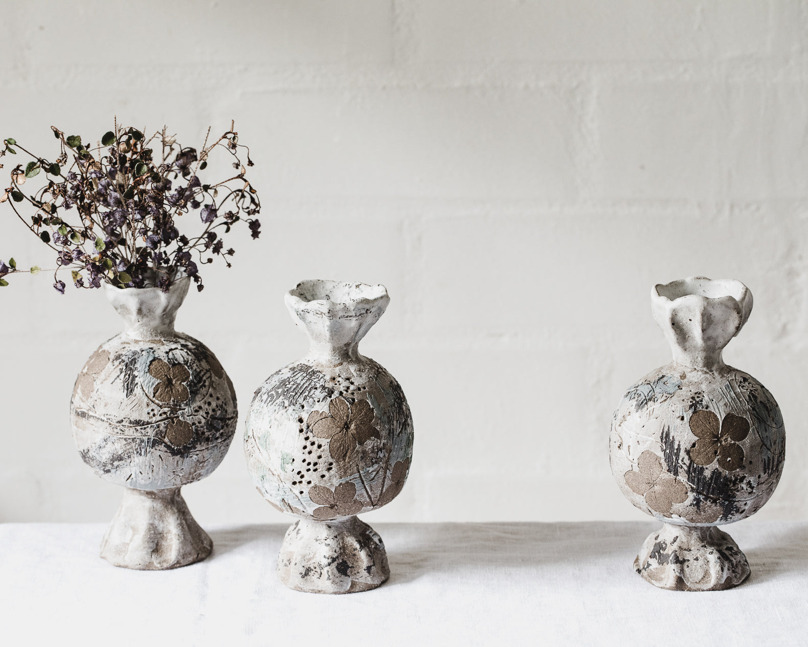 sculptural ceramic vessels with pedestal foot and rim impressed with hydrangea flowers in natural tones created by clay beehive ceramics