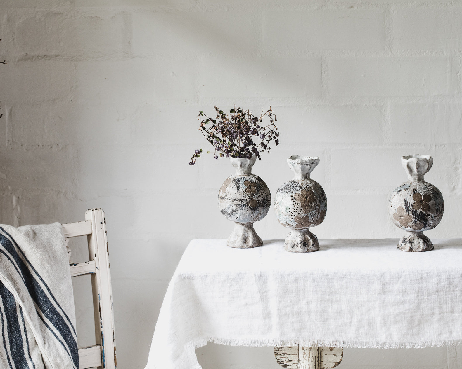 sculptural ceramic vessels with pedestal foot and rim impressed with hydrangea flowers in natural tones created by clay beehive ceramics