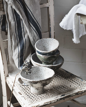 Rustic ceramic footed pedestal bowls sitting atop and old rustic chair in handcrafted by clay beehive ceramics 