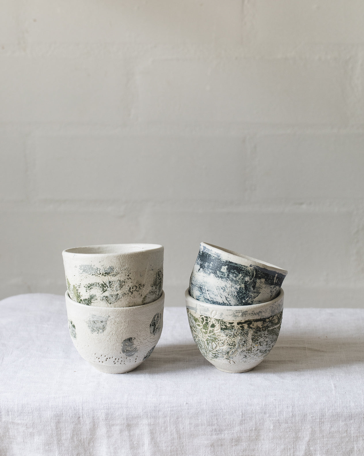 White footed cups with coloured patina surface textures hand made by clay beehive ceramics 