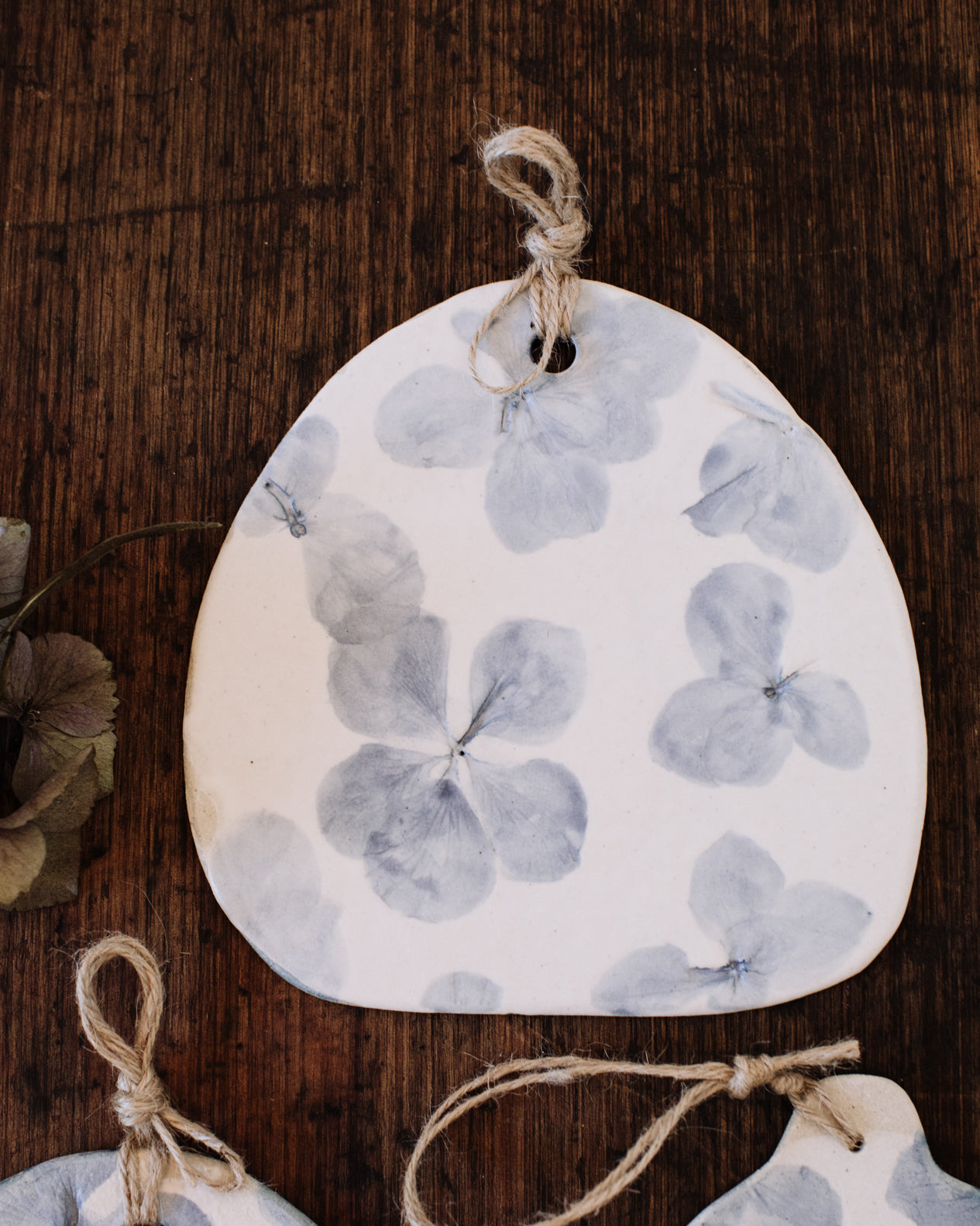 Hydrangea flowers impressions painted blue on clay beehive cheeseboards with hemp cord