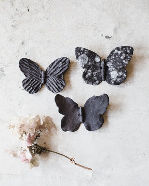 Black ceramic butterflies with white speckles and texture, wires attached for easy mounting and hanging, created by clay beehive ceramics