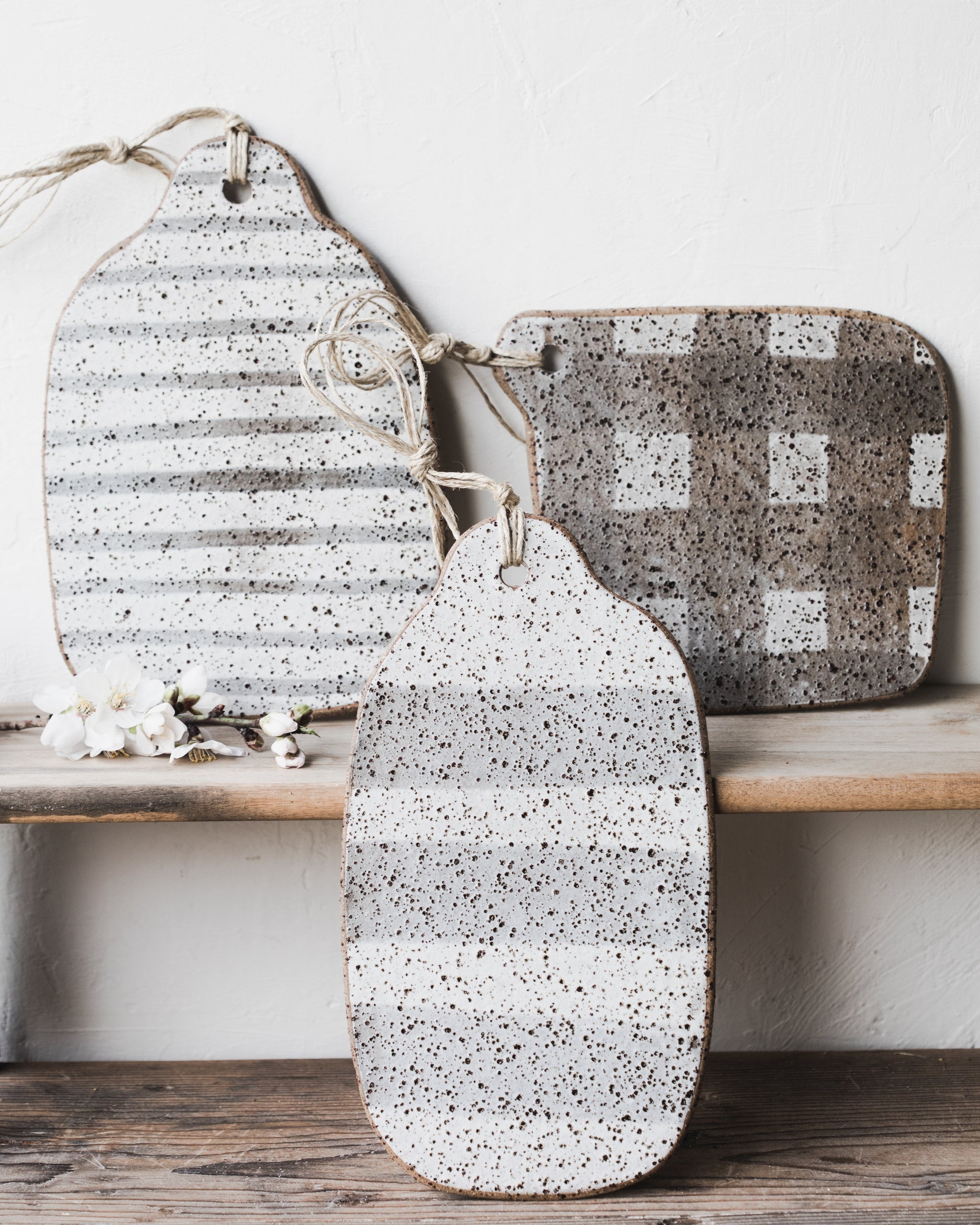 Handmade rustic speckled organic shaped cheeseboards with lines/grid patterns with hemp cord attached by clay beehive 