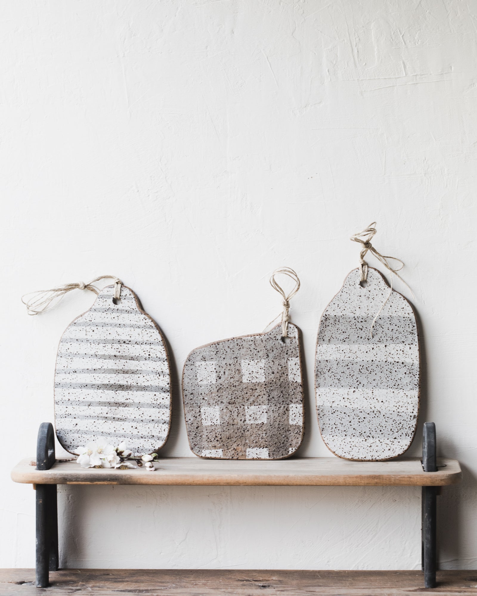 Handmade rustic speckled organic shaped cheeseboards with lines/grid patterns with hemp cord attached by clay beehive 