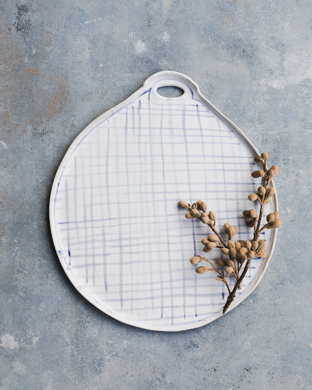 large round platter with cut out handle in a blue grid line pattern by clay beehive ceramics