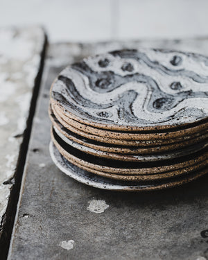 stack of hand made ceramic rustic gritty tapas sharing plates with carved designs glazed in satin black and white by clay beehive 